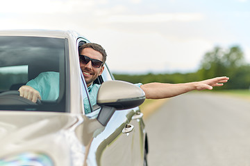 Image showing happy man in shades driving car and waving hand