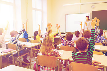 Image showing group of school kids raising hands in classroom