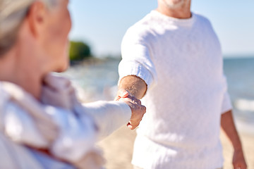 Image showing close up of senior couple holding hands on beach