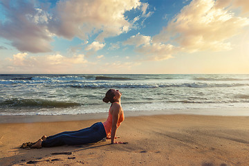 Image showing Woman practices yoga asana Urdhva Mukha Svanasana at the beach