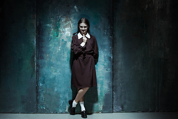 Image showing Portrait of a young smiling girl in school uniform as killer woman