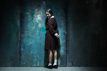 Image showing Portrait of a young smiling girl in school uniform as killer woman