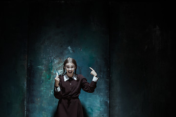 Image showing Portrait of a young smiling girl in school uniform as killer woman