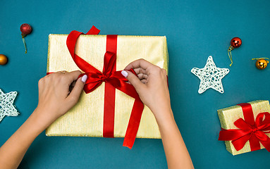 Image showing Hands of woman decorating Christmas gift box.