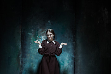 Image showing Portrait of a young smiling girl in school uniform as killer woman