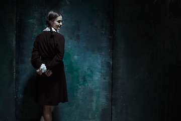 Image showing Portrait of a young smiling girl in school uniform as killer woman