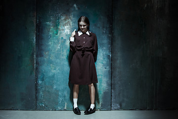 Image showing Portrait of a young smiling girl in school uniform as killer woman