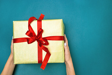 Image showing Female hands holding gift on blue background