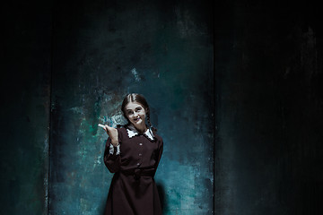 Image showing Portrait of a young smiling girl in school uniform as killer woman