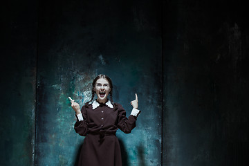 Image showing Portrait of a young smiling girl in school uniform as killer woman