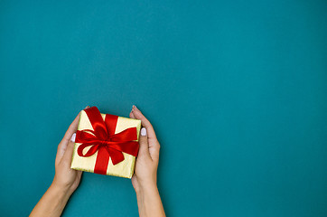 Image showing Female hands holding gift on blue background