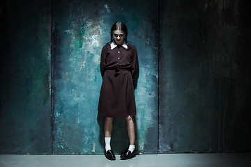 Image showing Portrait of a young smiling girl in school uniform as killer woman