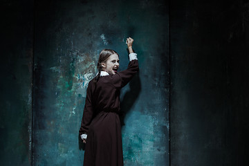 Image showing Portrait of a young smiling girl in school uniform as killer woman