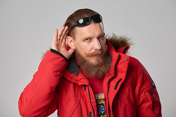 Image showing Man wearing red winter jacket with hand on ear