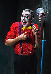 Image showing The scary clown and drip with blood on dack background. Halloween concept