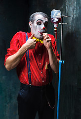 Image showing The scary clown and drip with blood on dack background. Halloween concept