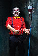 Image showing The scary clown and drip with blood on dack background. Halloween concept