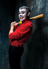 Image showing The scary clown and baseball-bat on dack background. Halloween concept