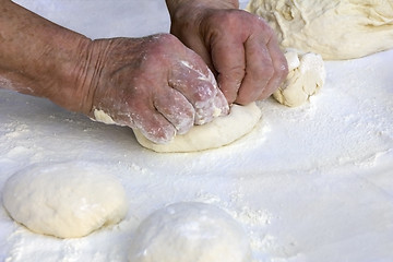 Image showing Older woman hands knead dough on a table in her home kitchen