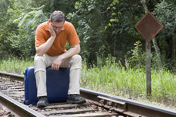 Image showing Man sitting on suitcase on a railway