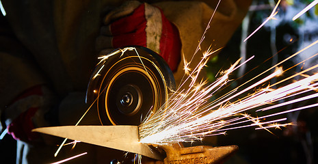 Image showing Worker cutting metal with grinder. Sparks while grinding iron