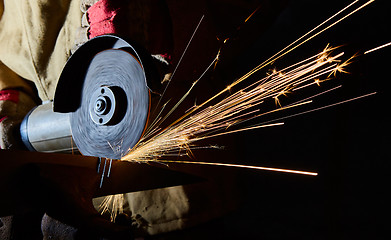 Image showing Worker cutting metal with grinder. Sparks while grinding iron