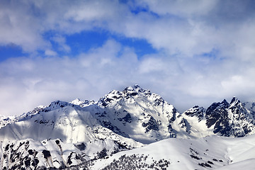 Image showing Snow slope and winter sunlight mountains in clouds