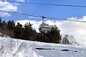 Image showing Skiers and snowboarders on chair-lift in winter mountain