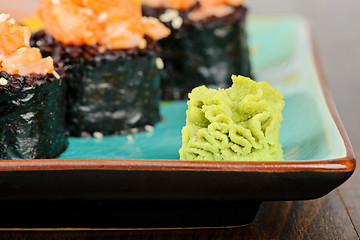 Image showing Wasabi with baked sushi rolls on turquoise plate