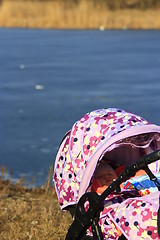 Image showing little baby sleeps in perambulator near the river