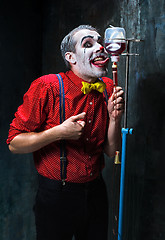 Image showing The scary clown and drip with blood on dack background. Halloween concept