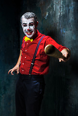 Image showing The scary clown and baseball-bat on dack background. Halloween concept