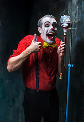 Image showing The scary clown and drip with blood on dack background. Halloween concept