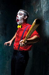 Image showing The scary clown and baseball-bat on dack background. Halloween concept