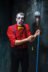 Image showing The scary clown and drip with blood on dack background. Halloween concept