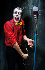 Image showing The scary clown and drip with blood on dack background. Halloween concept