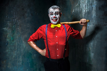 Image showing The scary clown and baseball-bat on dack background. Halloween concept