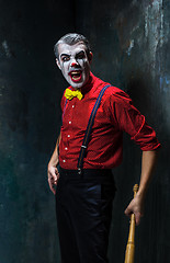 Image showing The scary clown and baseball-bat on dack background. Halloween concept