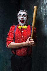 Image showing The scary clown and baseball-bat on dack background. Halloween concept