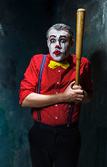 Image showing The scary clown and baseball-bat on dack background. Halloween concept