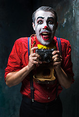 Image showing The scary clown and a camera on dack background. Halloween concept