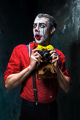 Image showing The scary clown and a camera on dack background. Halloween concept