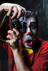 Image showing The scary clown and a camera on dack background. Halloween concept