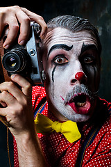 Image showing The scary clown and a camera on dack background. Halloween concept