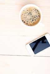 Image showing Cup of coffee with foam on wooden table