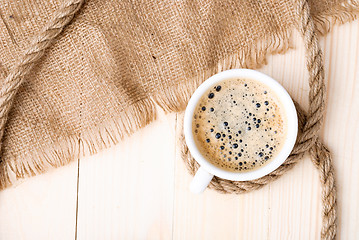 Image showing Cup of coffee with foam on wooden table