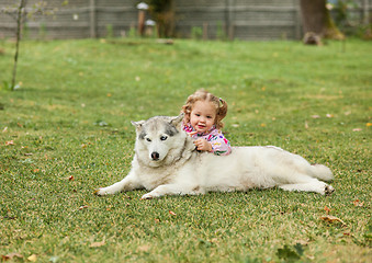 Image showing The little baby girl playing with dog against green grass