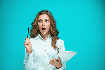 Image showing Surprised young business woman with tablet for notes on blue background