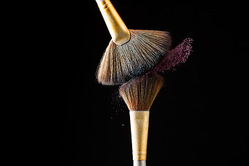 Image showing Make-up brushes with pink powder isolated on black background