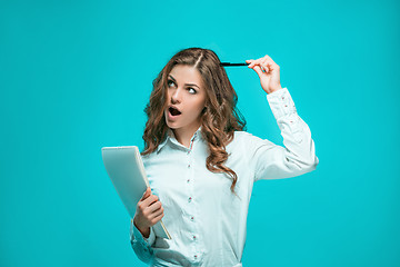 Image showing The thoughtful young business woman with pen and tablet for notes on blue background